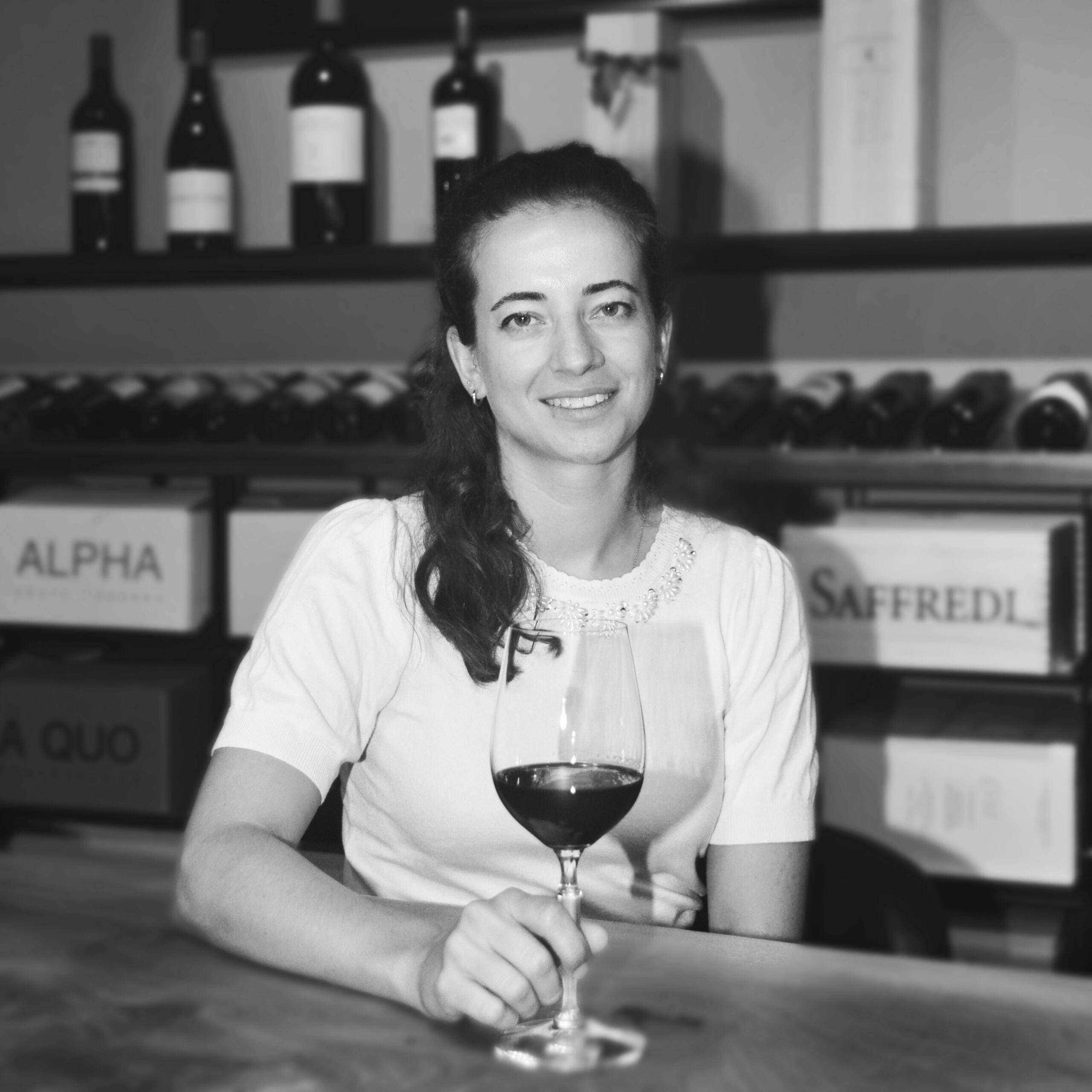 Deborah Wagner, Marketing und Kommunikation, sitzt am Tisch mit einem Glas Rotwein - Vinothek Denz Weine Zürich