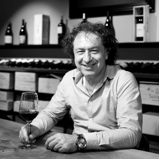 Goran Milenkovic am Tisch mit einem Glas Rotwein - Vinothek Denz Weine Zürich