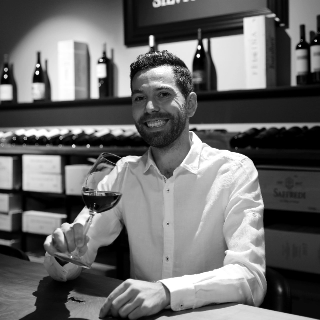 Helder Lopes am Tisch mit einem Glas Rotwein - Vinothek Denz Weine Zürich