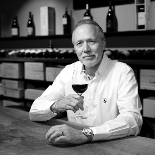 Weinexperte und COO Marco Caluori am Tisch mit einem Glas Rotwein - Vinothek Denz Weine Zürich