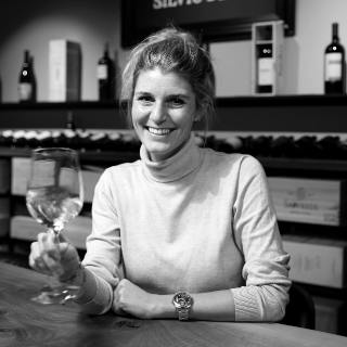 Weinexpertin Nina Schoch am Tisch mit einem Glas Weisswein - Vinothek Denz Weine Zürich