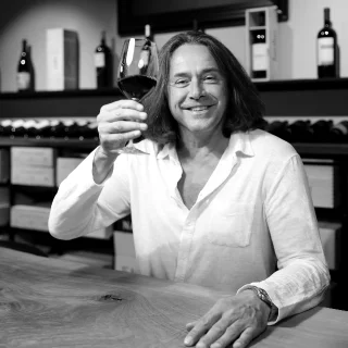 Weinexperte Roger Stadelmann am Tisch mit einem Glas Rotwein - Denz Weine Zürich
